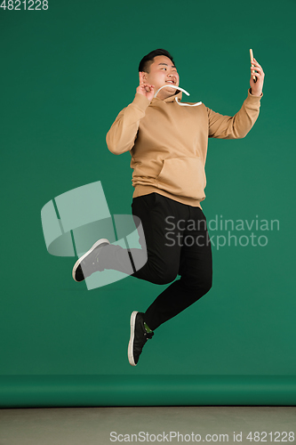 Image of Asian man\'s portrait isolated over green studio background with copyspace