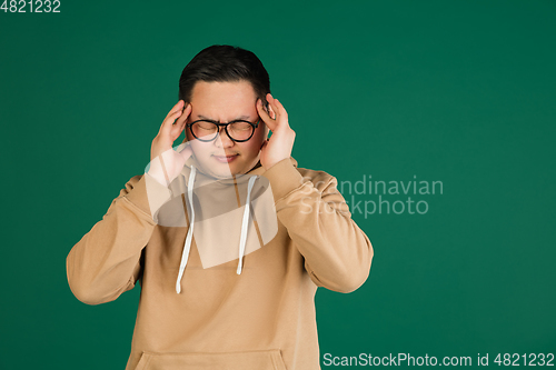 Image of Asian man\'s portrait isolated over green studio background with copyspace