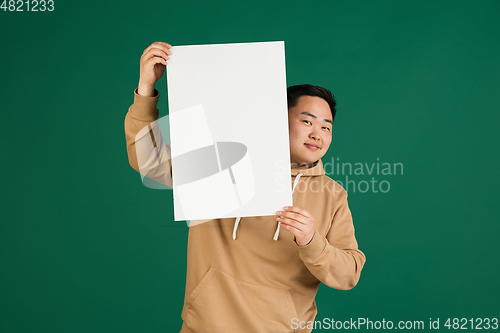 Image of Asian man\'s portrait isolated over green studio background with copyspace