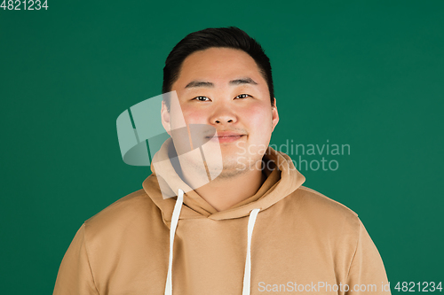 Image of Asian man\'s portrait isolated over green studio background with copyspace