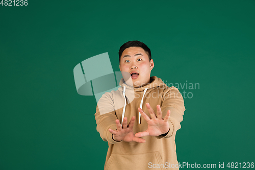 Image of Asian man\'s portrait isolated over green studio background with copyspace