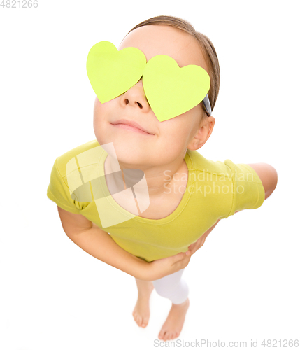 Image of Little girl is holding hearts over her eyes