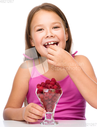 Image of Happy little girl is eating raspberries