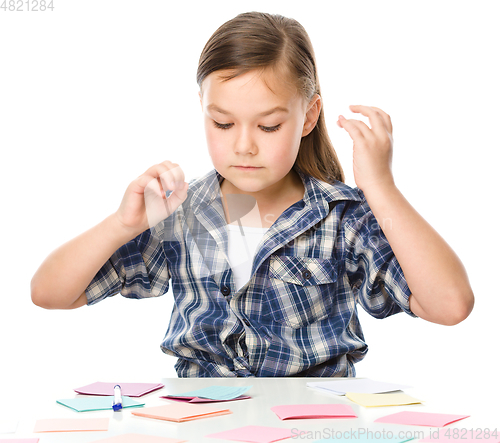 Image of Girl is writing on color stickers using pen