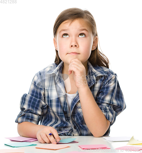 Image of Girl is writing on color stickers using pen