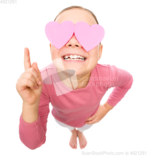 Image of Little girl is holding hearts over her eyes