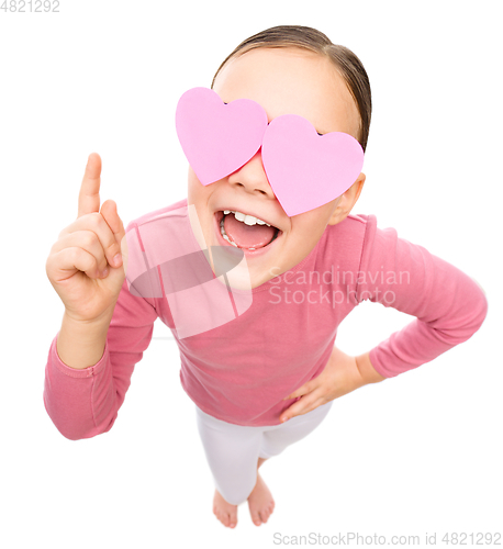 Image of Little girl is holding hearts over her eyes