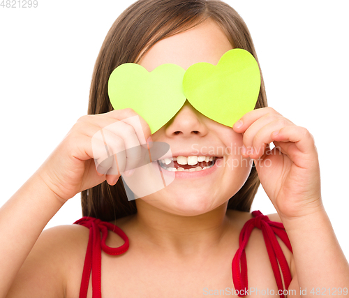 Image of Little girl is holding hearts over her eyes