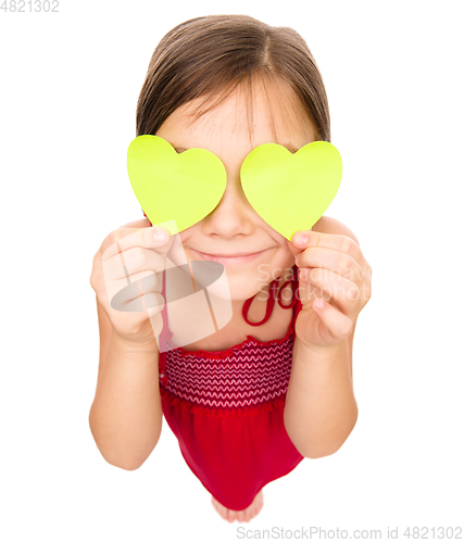 Image of Little girl is holding hearts over her eyes