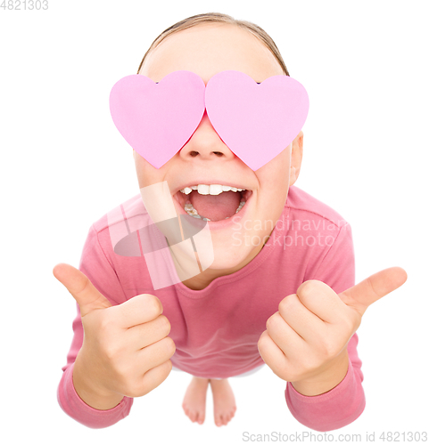 Image of Little girl is holding hearts over her eyes