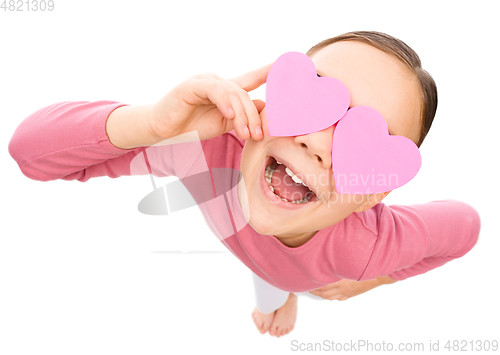 Image of Little girl is holding hearts over her eyes