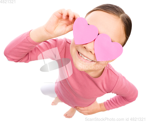 Image of Little girl is holding hearts over her eyes