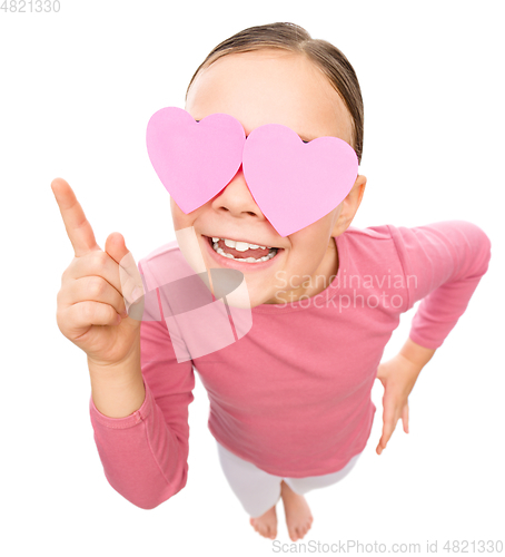 Image of Little girl is holding hearts over her eyes