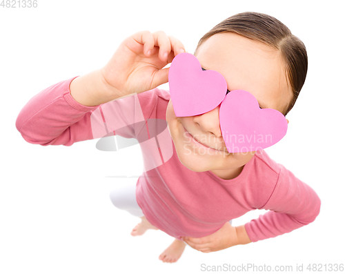 Image of Little girl is holding hearts over her eyes