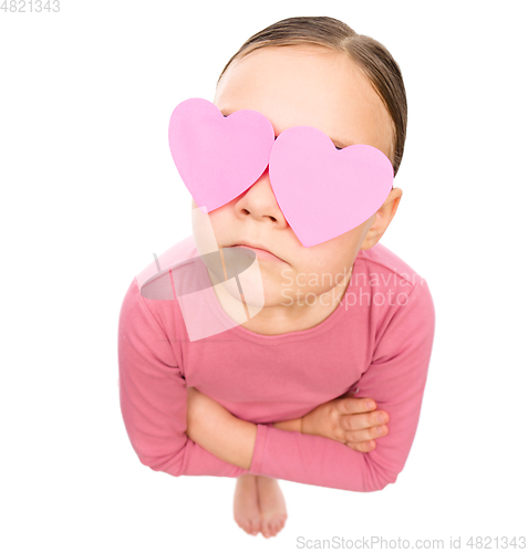 Image of Little girl is holding hearts over her eyes