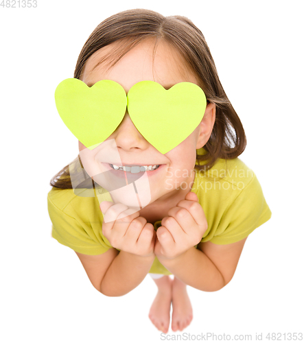 Image of Little girl is holding hearts over her eyes