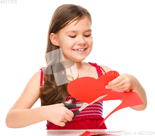 Image of Portrait of a little girl cutting out red heart