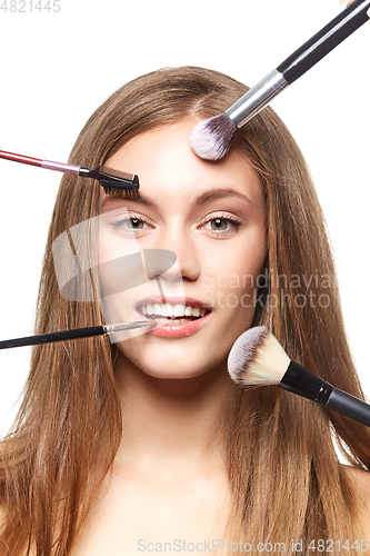 Image of beautiful girl with makeup brushes
