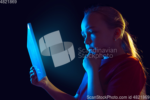 Image of Caucasian girl\'s portrait isolated on dark studio background in neon light