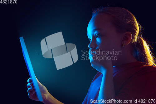 Image of Caucasian girl\'s portrait isolated on dark studio background in neon light