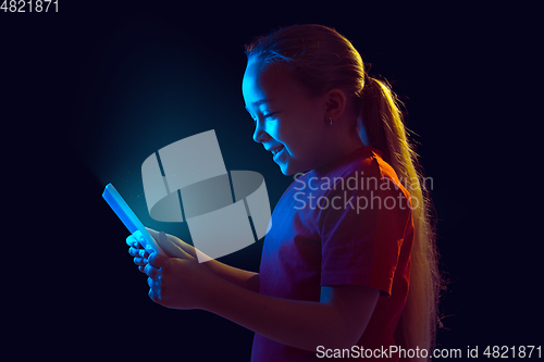 Image of Caucasian girl\'s portrait isolated on dark studio background in neon light