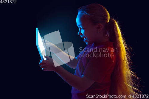 Image of Caucasian girl\'s portrait isolated on dark studio background in neon light