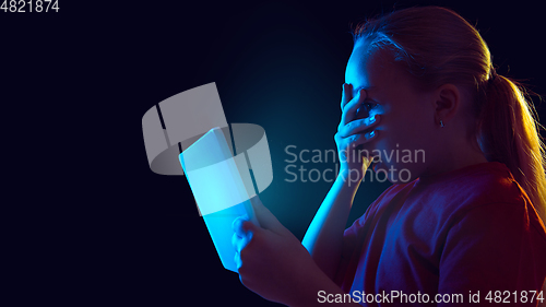 Image of Caucasian girl\'s portrait isolated on dark studio background in neon light