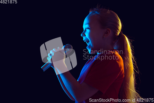 Image of Caucasian girl\'s portrait isolated on dark studio background in neon light