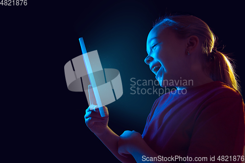 Image of Caucasian girl\'s portrait isolated on dark studio background in neon light