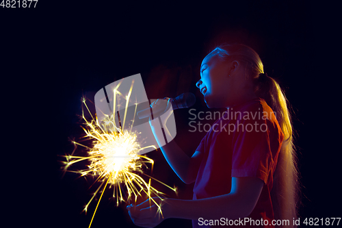 Image of Caucasian girl\'s portrait isolated on dark studio background in neon light