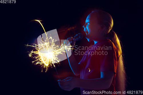 Image of Caucasian girl\'s portrait isolated on dark studio background in neon light