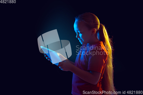 Image of Caucasian girl\'s portrait isolated on dark studio background in neon light