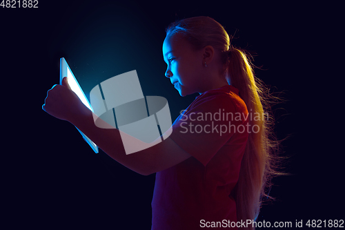 Image of Caucasian girl\'s portrait isolated on dark studio background in neon light