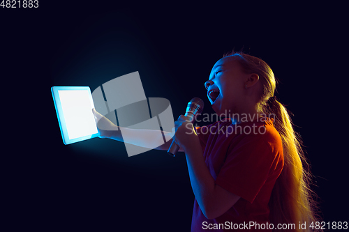 Image of Caucasian girl\'s portrait isolated on dark studio background in neon light