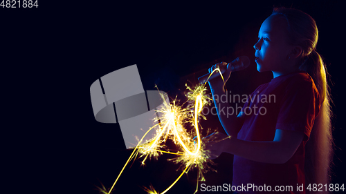 Image of Caucasian girl\'s portrait isolated on dark studio background in neon light