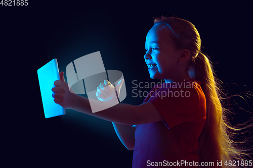 Image of Caucasian girl\'s portrait isolated on dark studio background in neon light