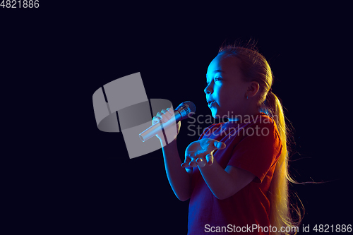 Image of Caucasian girl\'s portrait isolated on dark studio background in neon light