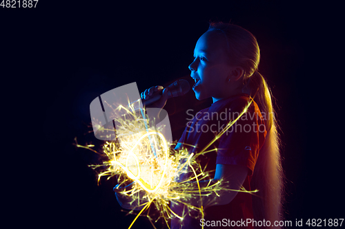 Image of Caucasian girl\'s portrait isolated on dark studio background in neon light