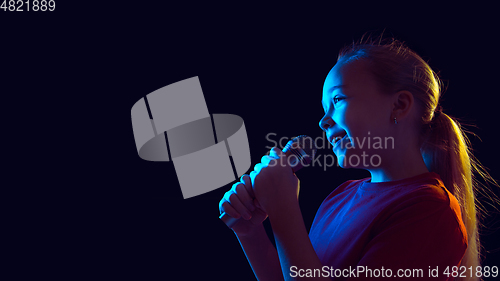 Image of Caucasian girl\'s portrait isolated on dark studio background in neon light