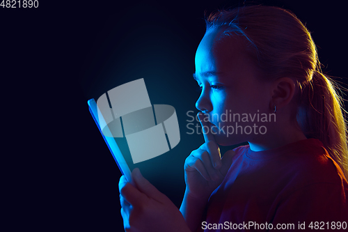 Image of Caucasian girl\'s portrait isolated on dark studio background in neon light
