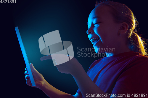 Image of Caucasian girl\'s portrait isolated on dark studio background in neon light