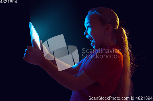 Image of Caucasian girl\'s portrait isolated on dark studio background in neon light