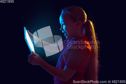 Image of Caucasian girl\'s portrait isolated on dark studio background in neon light