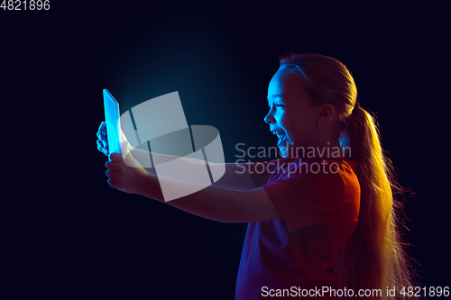 Image of Caucasian girl\'s portrait isolated on dark studio background in neon light