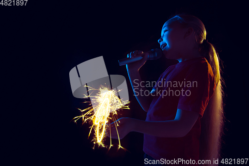 Image of Caucasian girl\'s portrait isolated on dark studio background in neon light