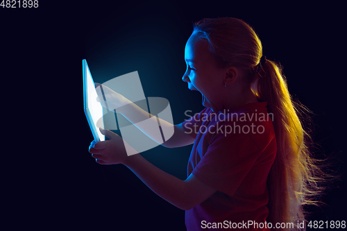 Image of Caucasian girl\'s portrait isolated on dark studio background in neon light