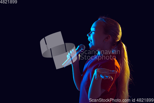 Image of Caucasian girl\'s portrait isolated on dark studio background in neon light