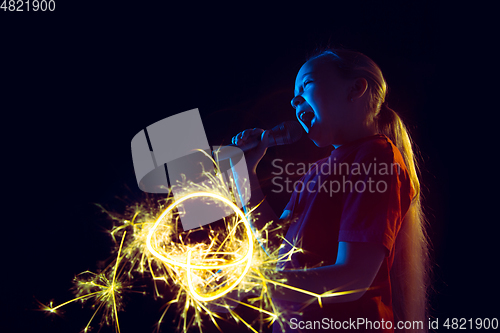 Image of Caucasian girl\'s portrait isolated on dark studio background in neon light