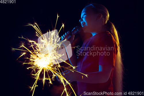 Image of Caucasian girl\'s portrait isolated on dark studio background in neon light