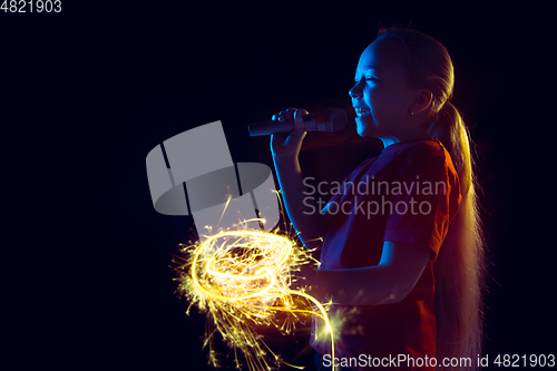 Image of Caucasian girl\'s portrait isolated on dark studio background in neon light